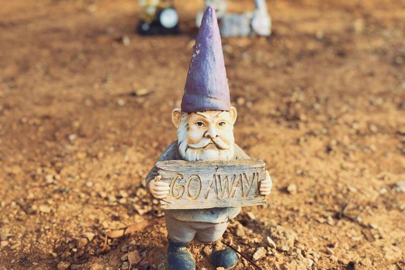 garden gnome holding sign saying 'go away'