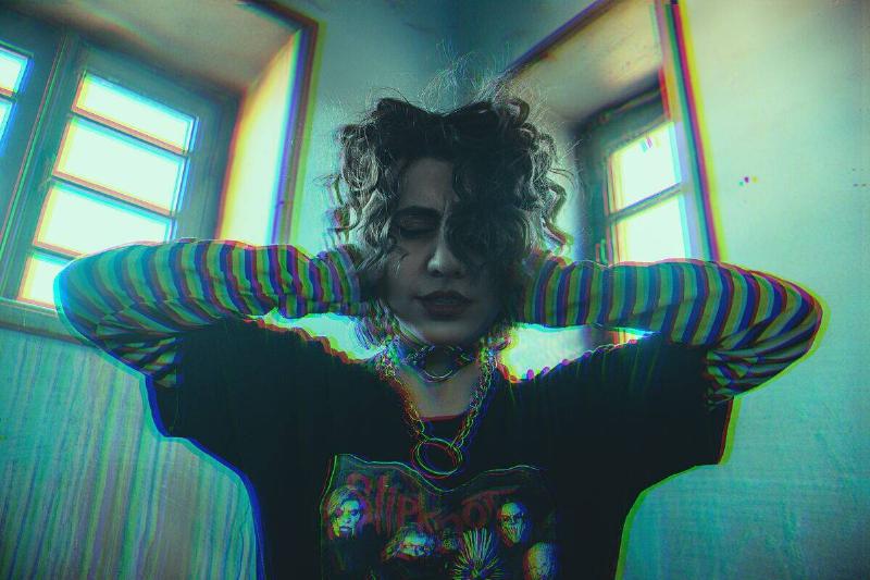 woman in Slipknot T-shirt covering her ears among retro filter