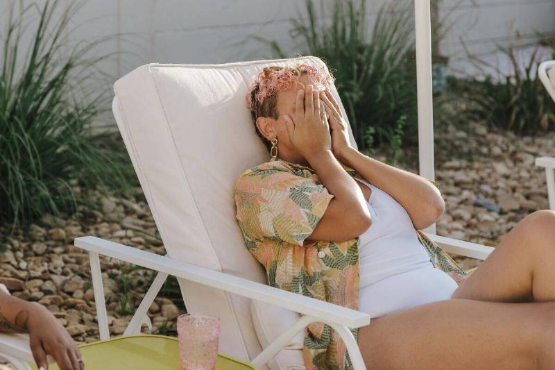 woman in pool chair covering her face with her hands
