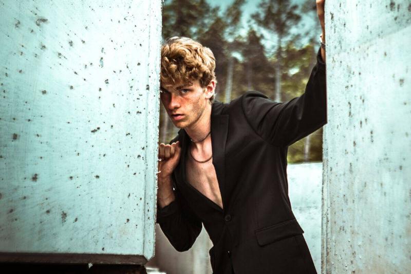 Man in fashionable suit posing between large concrete blocks