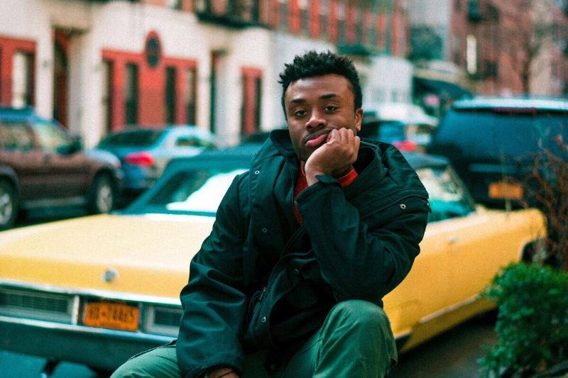 man sitting with face in hand behind yellow car