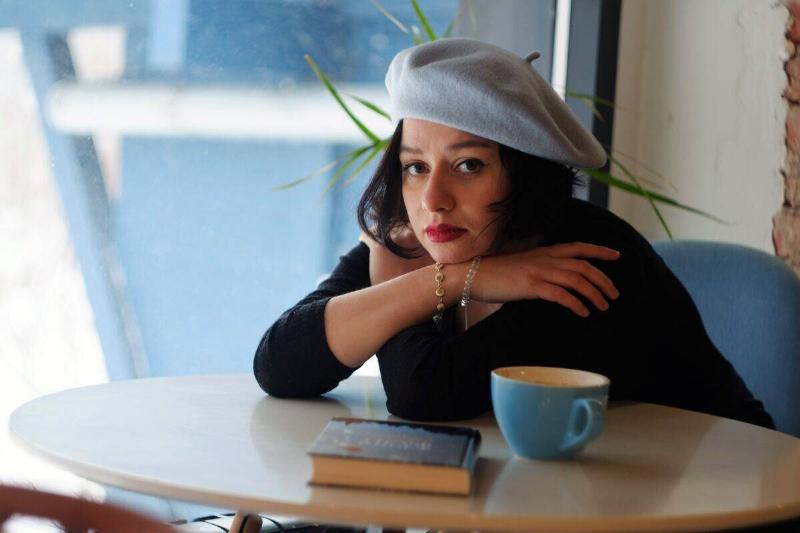 woman in beret leaning on table next to coffee mug