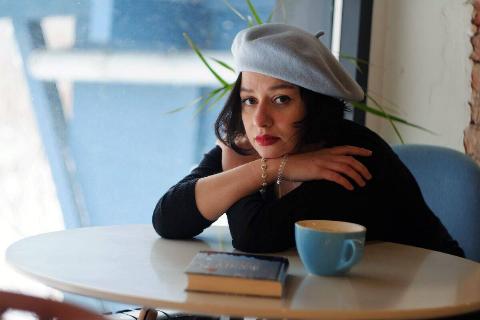 woman in beret leaning on table next to coffee mug