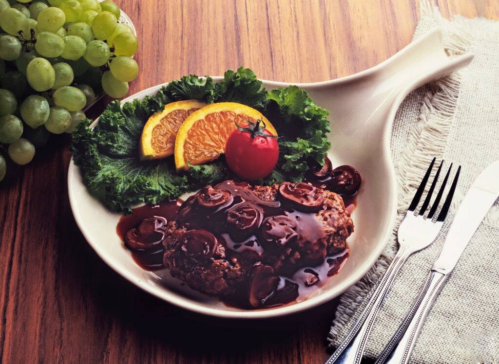 Salisbury steak with mushrooms on white plate with garnish