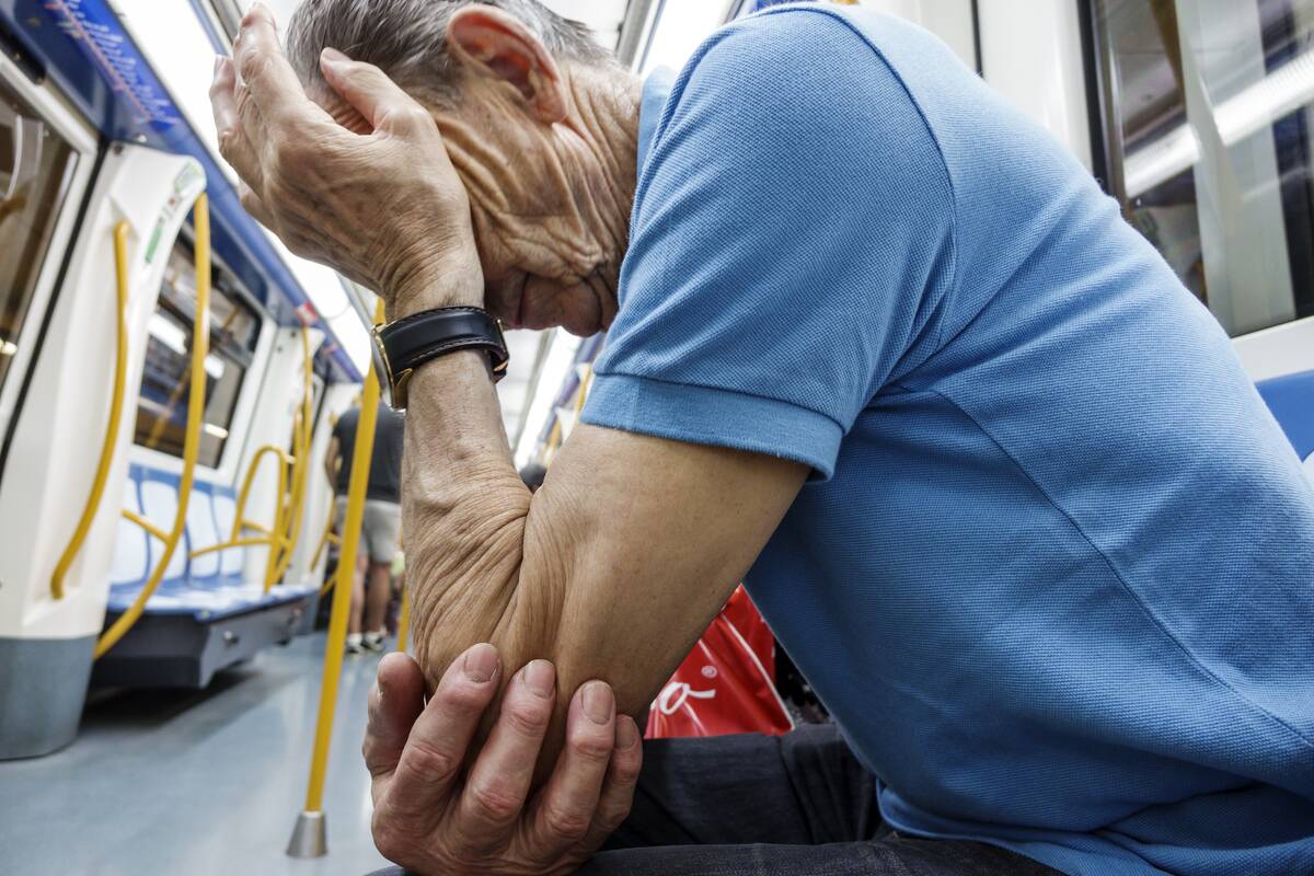 A senior man resting his head on his hand on a train at Alonzo Martinez Metro Station.