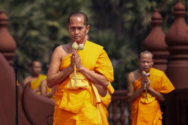 Thai Buddhist monks hold flowers as they pay obeisance to...
