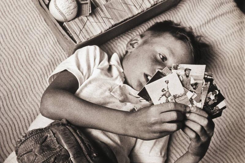 Boy Lying on Bed Studying Baseball Cards