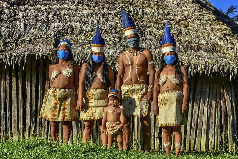 Colombian Huitoto indigenous people pose wearing face masks.