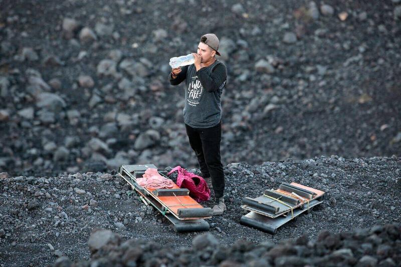 An employee of a tour company drinks water after climbing the Cerro Negro volcano.