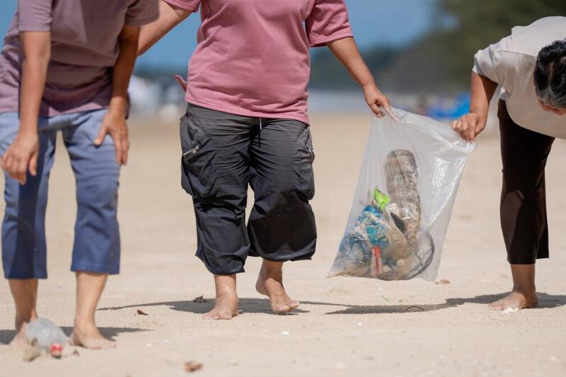 A group of people cleaning up trash on the beach.