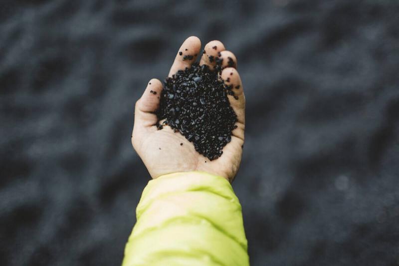 Hand holding black asphalt granules. 