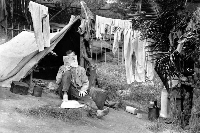 A homeless man reads 'How to End Capitalism'