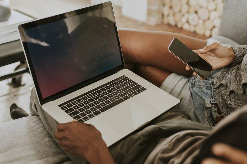 Couple using a laptop and a mobile phone.