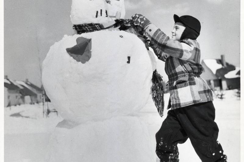 Boy Tying Scarf Around Snowman