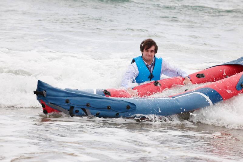 Man pushing canoe in cold water.