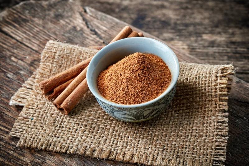 Cinnamon sticks and powder on wooden table.