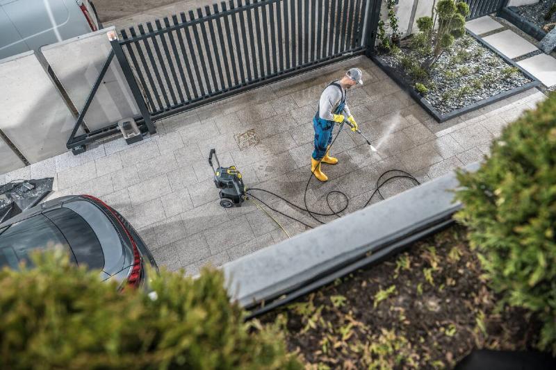 Man cleaning driveway with pressure washer.