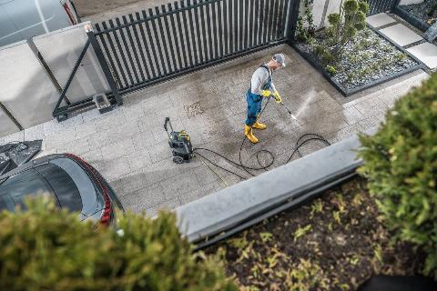 Man cleaning driveway with pressure washer.