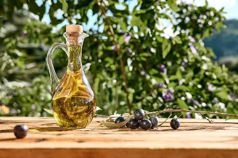 Extra virgin olive oil and olive branch in the bottle on wooden table in the olive grove.
