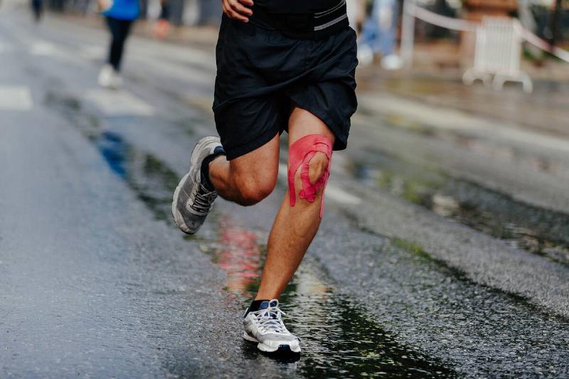 Man running with athletic tape on knee.