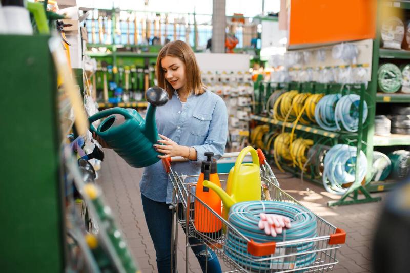 Female customer choosing gardening tools in shop for gardeners.