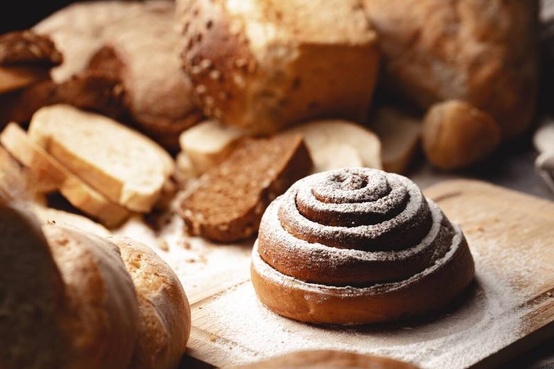 Fresh cinnamon bun roll with sugar powder on wooden board.