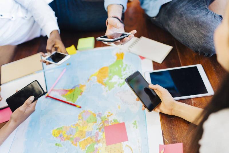 People sitting around map with phones.