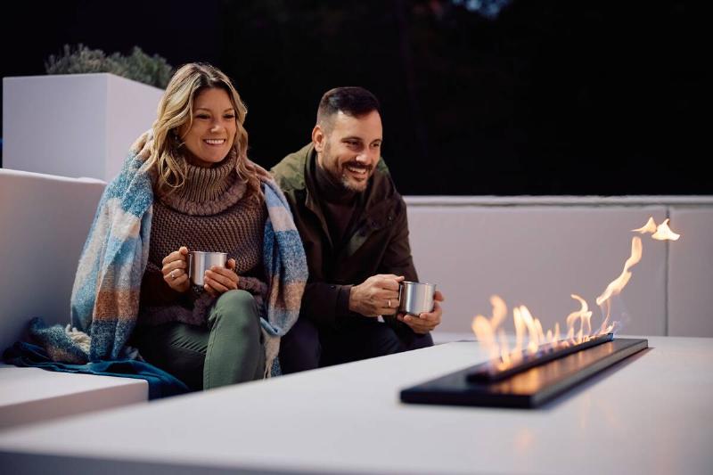 Couple relaxing by fire on deck.