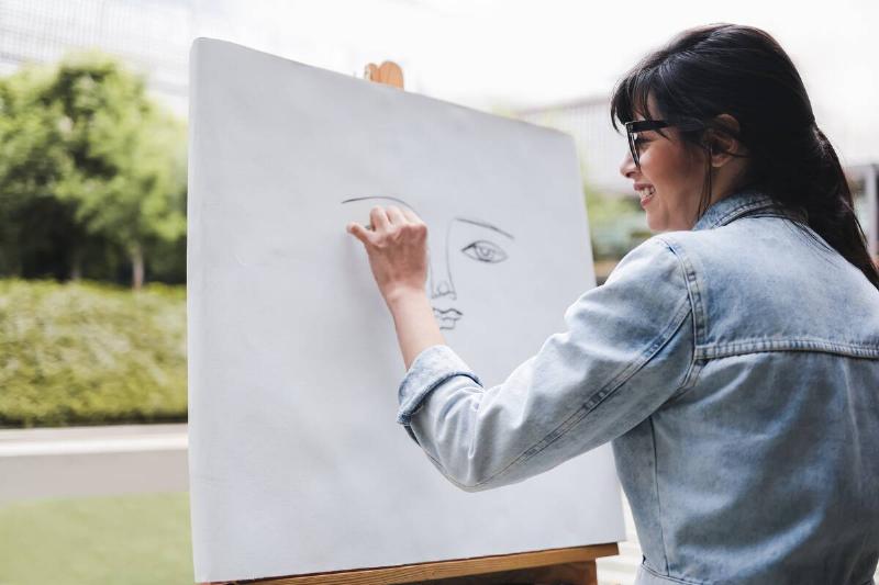 Young artist painting outside. 