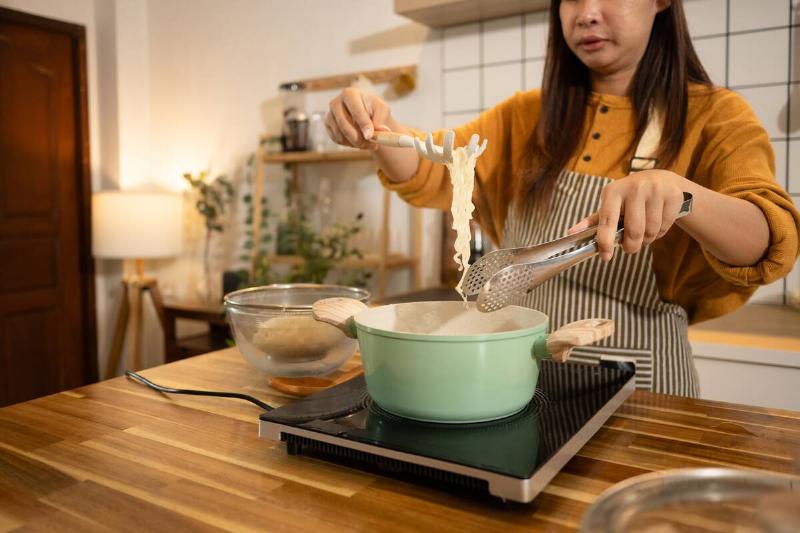 Woman making noodles in kitchen.