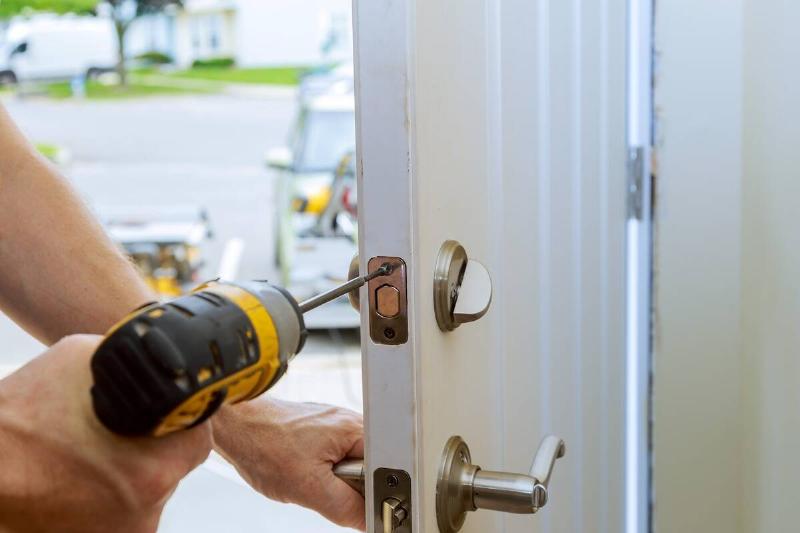 Worker's hands installing new door deadbolt. 