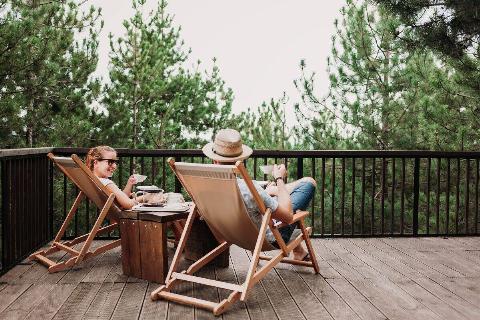 A couple sitting on a deck, drinking coffee. 