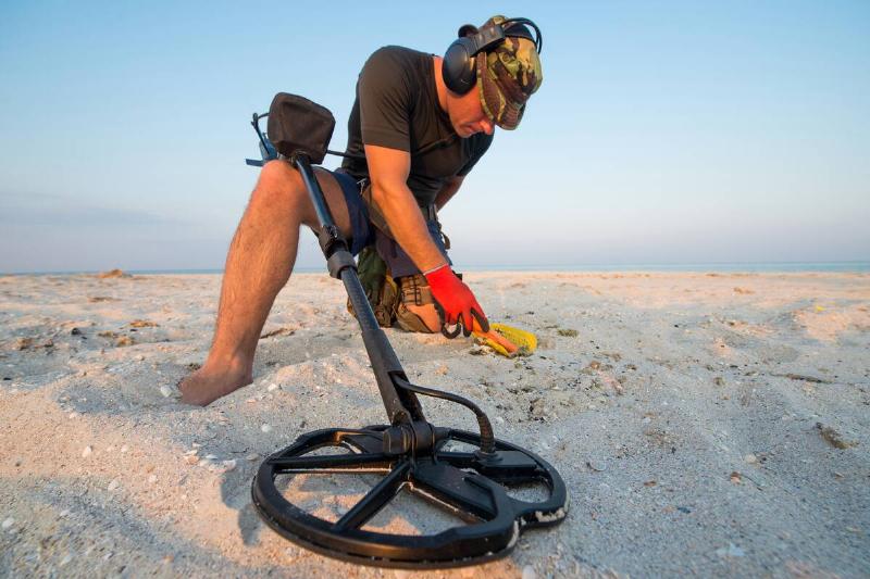 Man with a metal detector on a sea sandy beach.
