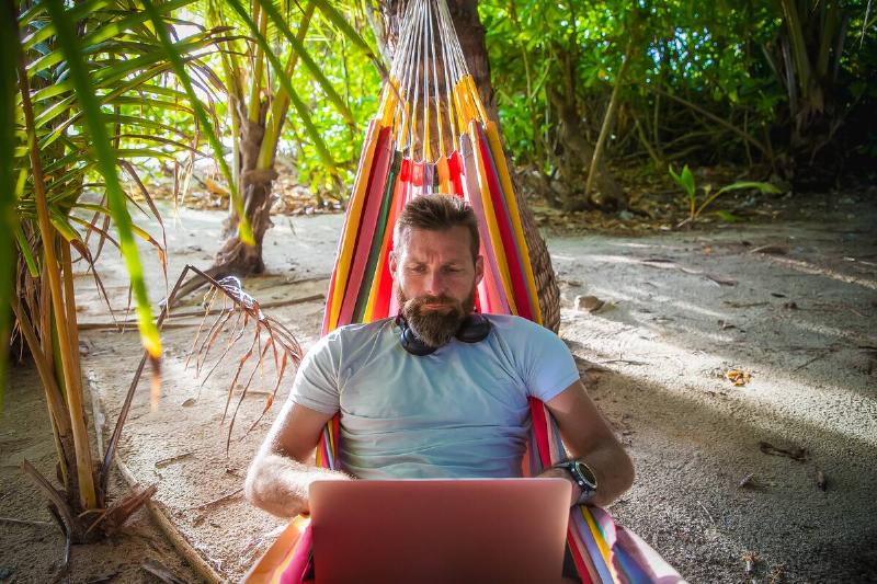 Man working on laptop on exotic beach.