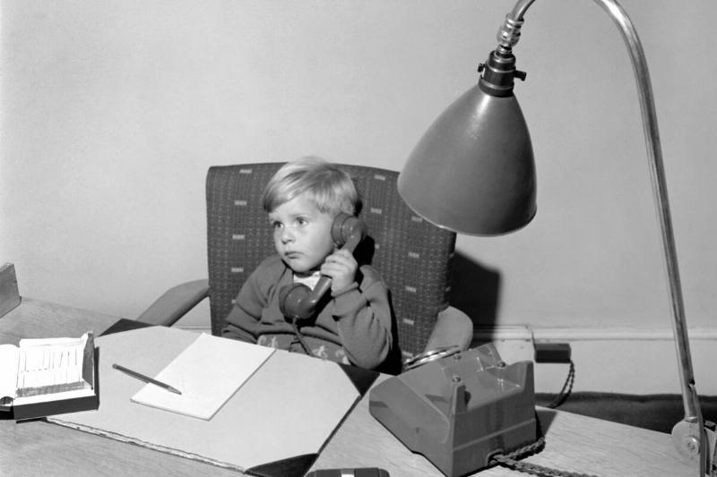 Office Junior: Two year old boy helps out at the offices of Theobald and son. 1957