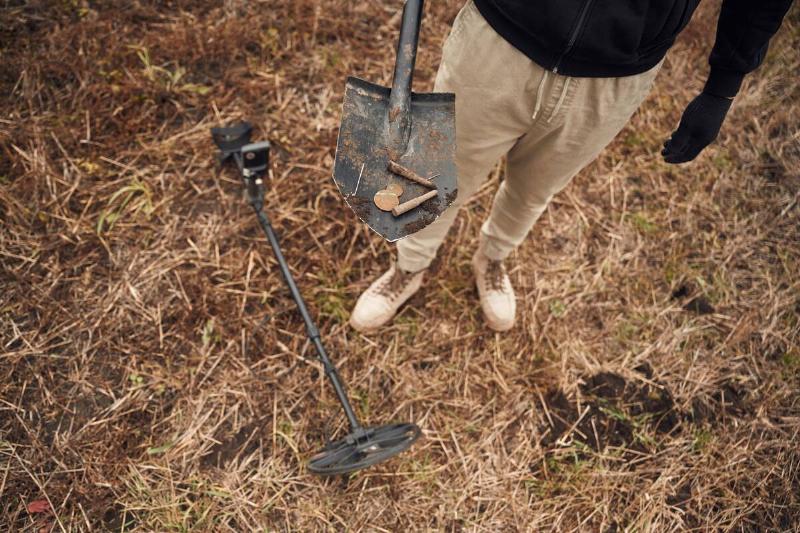 Old bullets and coin. Man is with metal detector in the field.