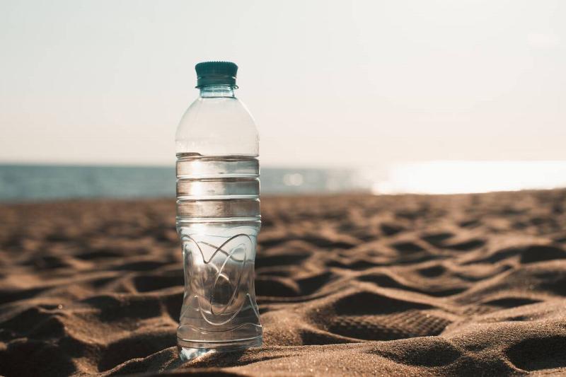Plastic bottle of water standing on the beach.