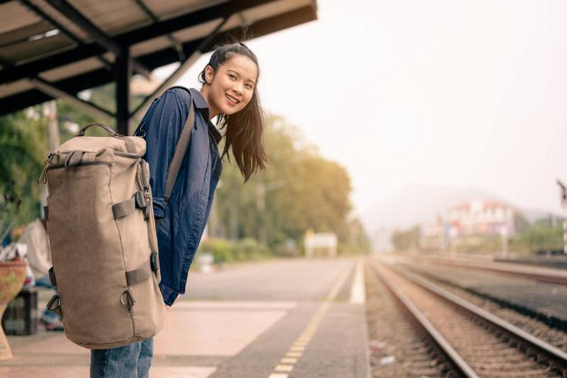 A female passenger with backpack on railroad platform.