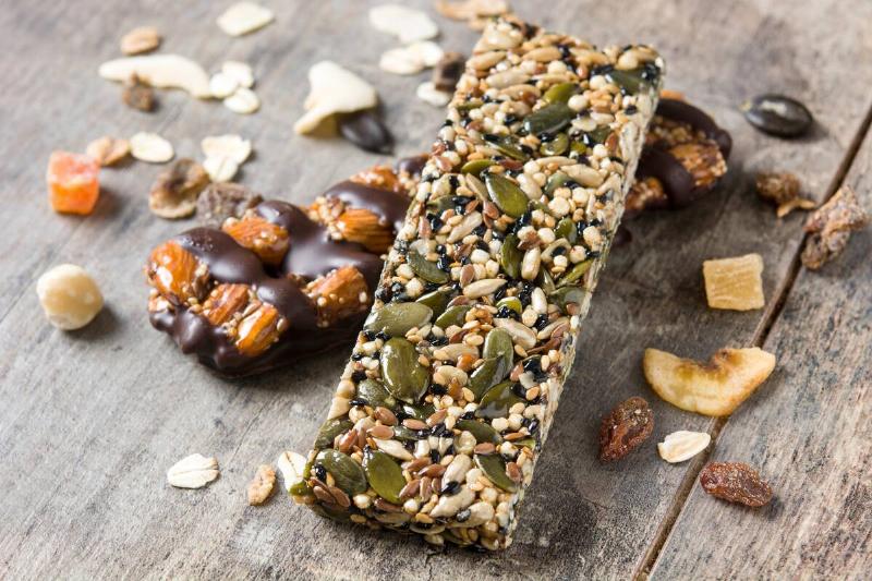 Two protein bars with nuts, seeds, chocolate and dried fruits.