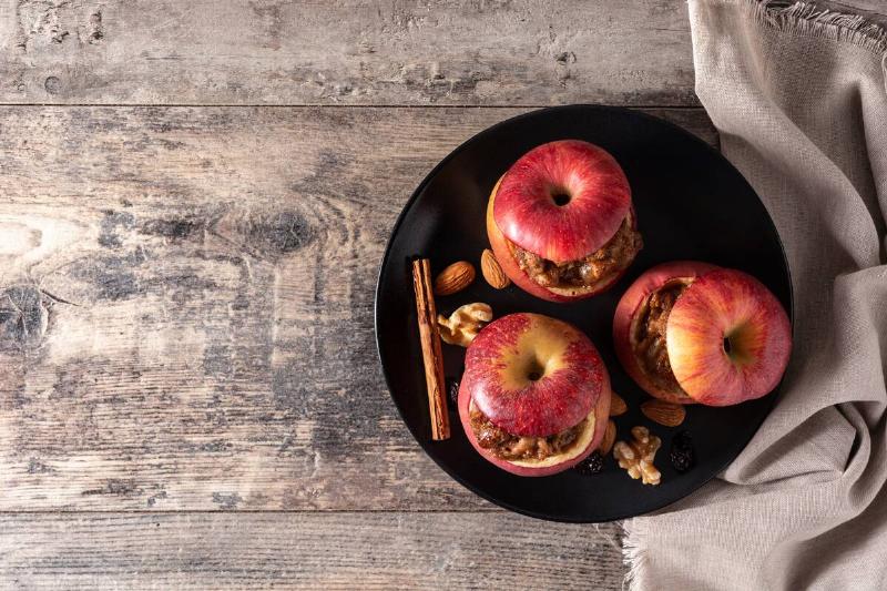 Stuffed apples baked with nuts on wooden table.
