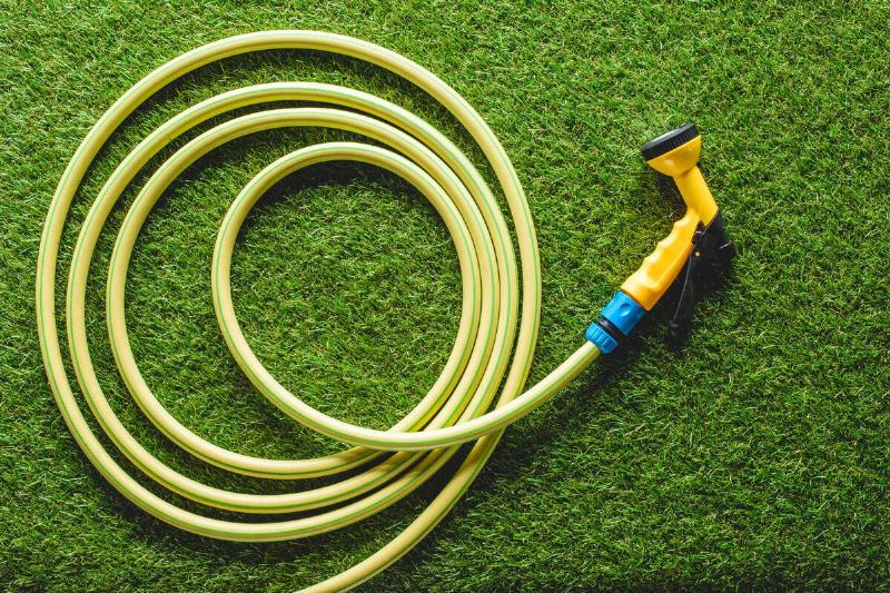 A hose and spray nozzle on grass. 