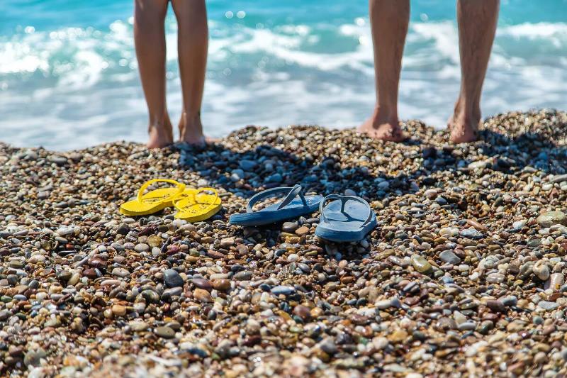 Flip-flops and feet on the beach at the sea.