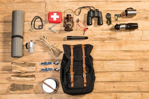 Survival bag and items on wooden floor. 