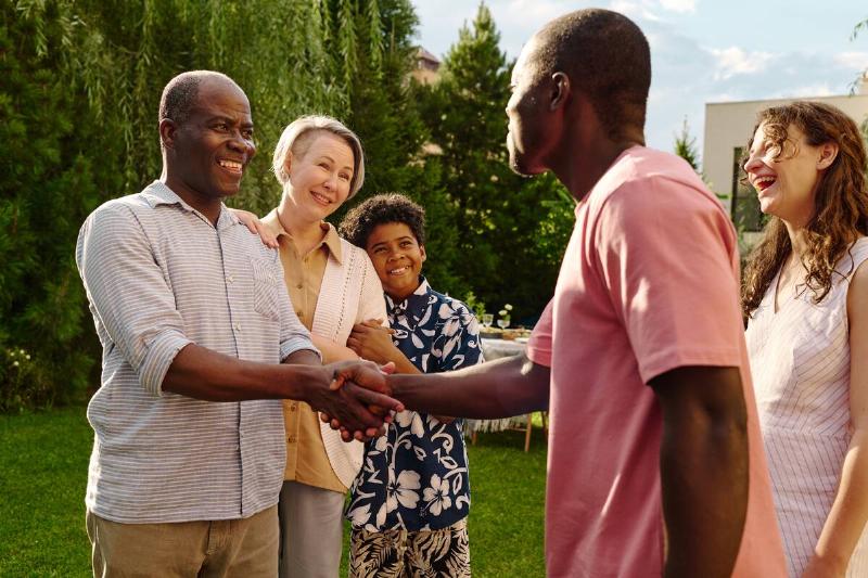 Two men shaking hands with their families. 
