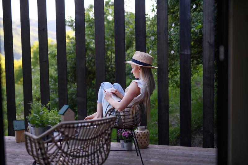 Woman reading a book on a deck.