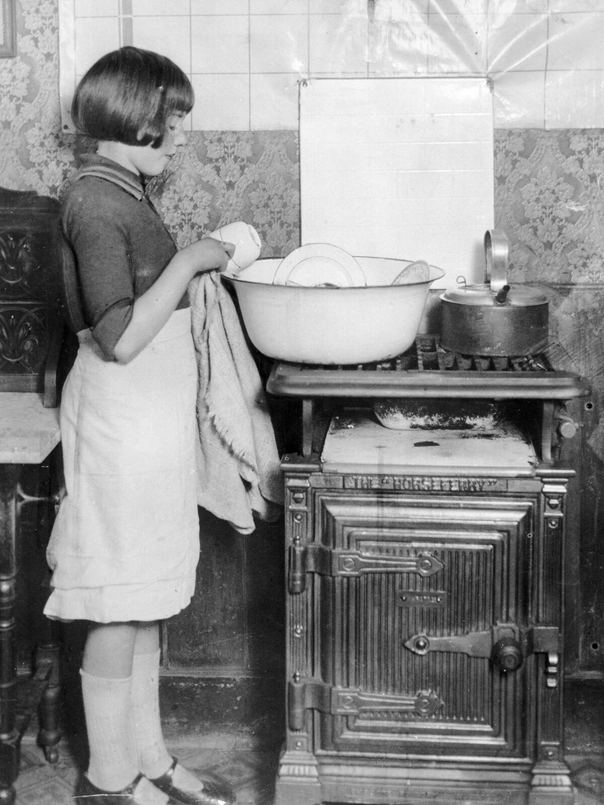 Young girl washing-up the dishes, 5 December 1930