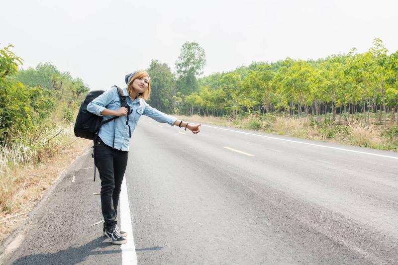 Young hipster woman hitchhiking.