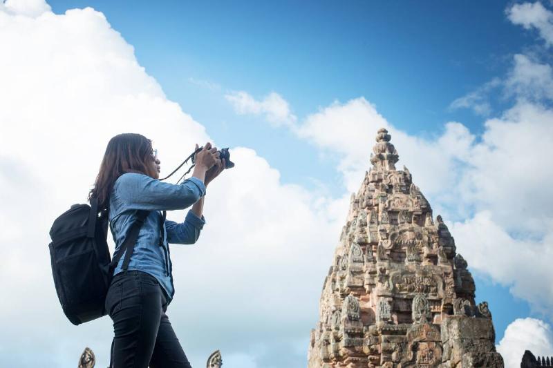 Young woman tourist with backpack coming to shoot photo at ancient phanom rung temple in thailand.