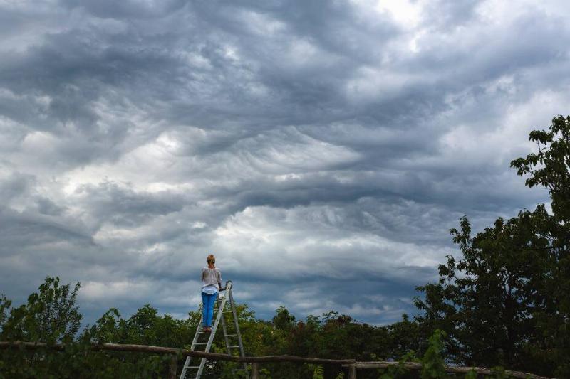 Woman on ladder in storm.