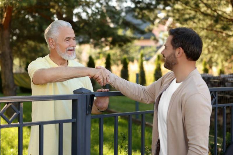 Two men shaking hands over fence.